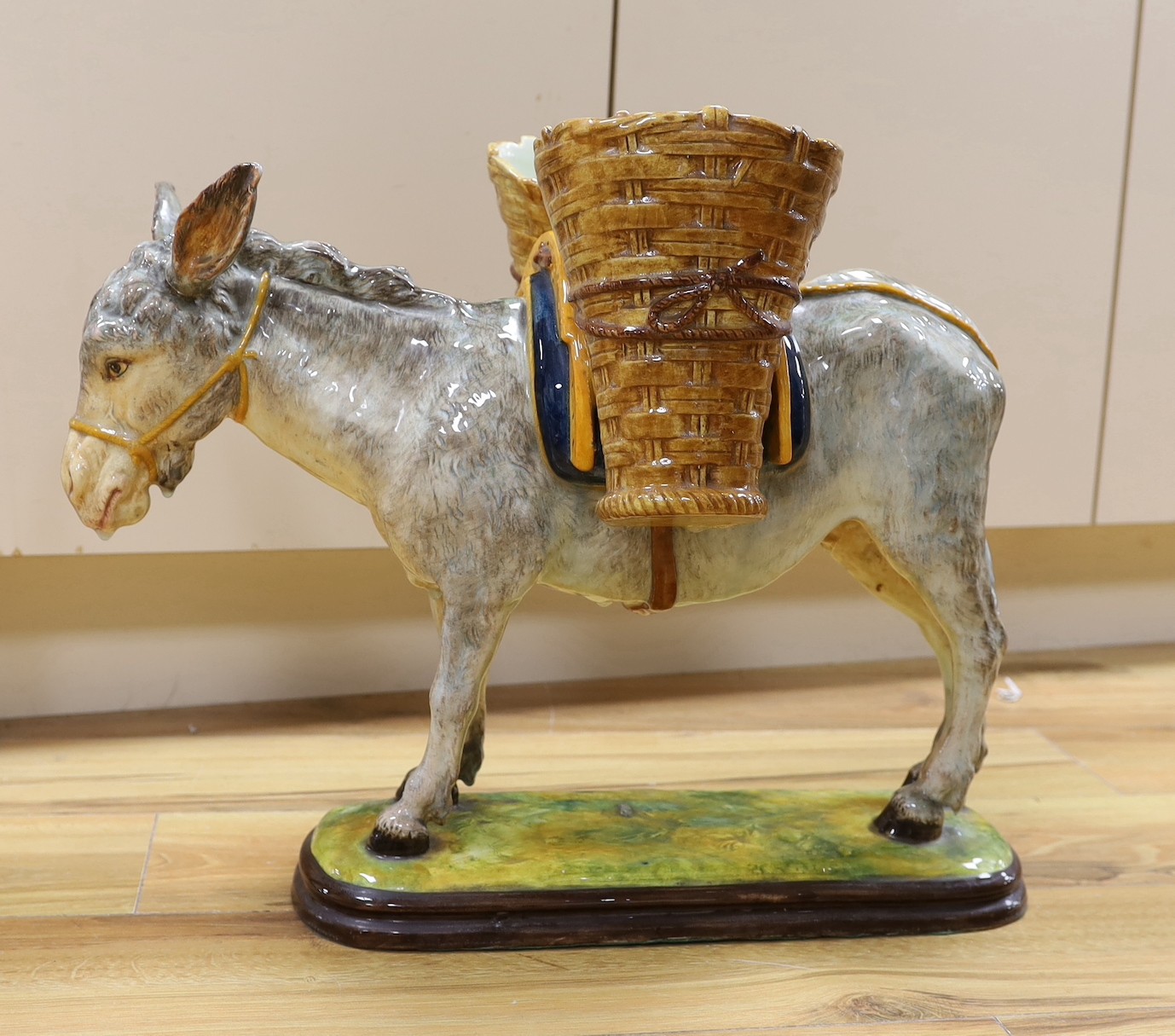 A large 20th century Italian maiolica model of a donkey with basket work panniers - 56cm long